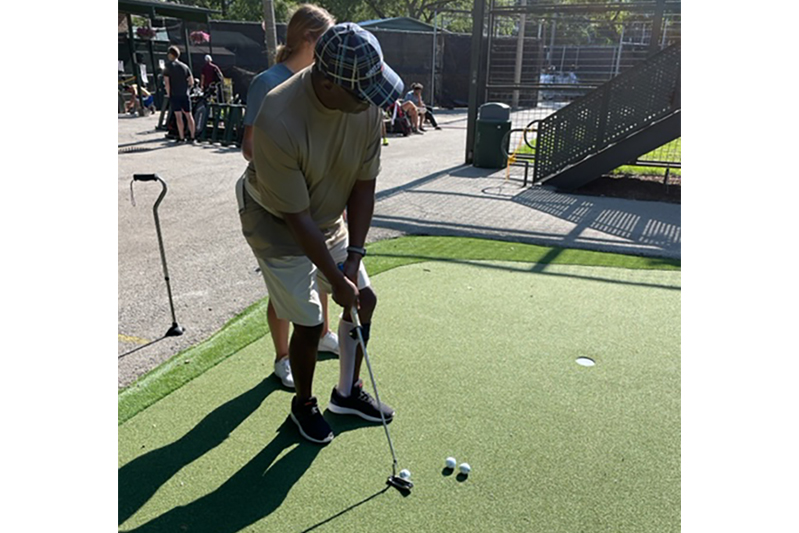 An SRAlab adaptive golfer lines up a putt.