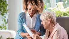 This is a picture of a black nurse and an elderly white woman working together to address the patients' care plan.