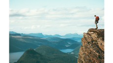 white backpacker looking out at the top of a cliff