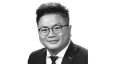 black and white photo of an Asian man with glasses and wearing a suit.
