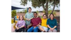 color photo of several people gathered on a park bench