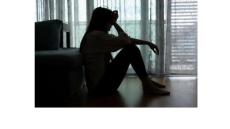 a silhouette of a young woman sitting on the floor with her head in her hands 