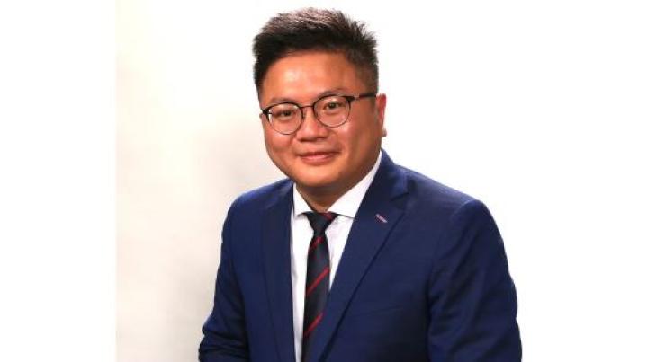 a Chinese man with black hair and glasses wearing a suit is smiling. The picture is black and white