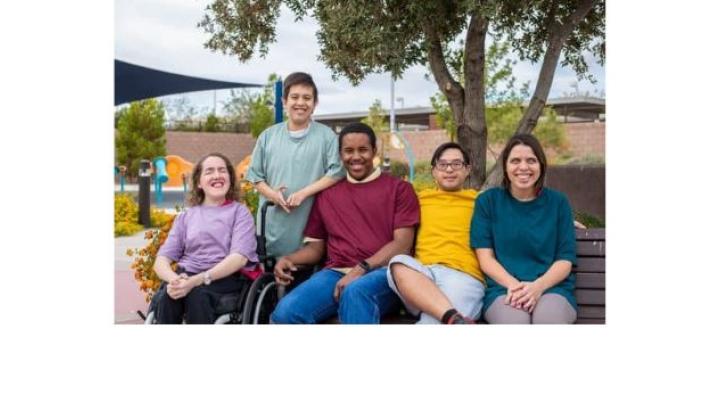 color photo of several people gathered on a park bench