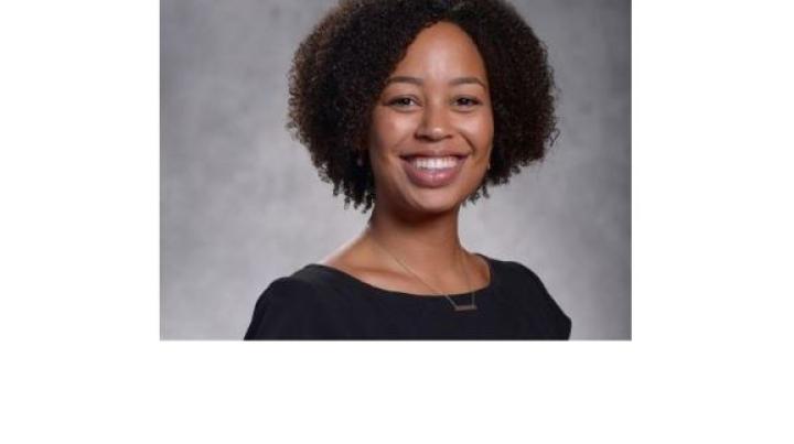 color photo of diminique kinnet hopkins, a young Black woman with short curly black hair and a black top