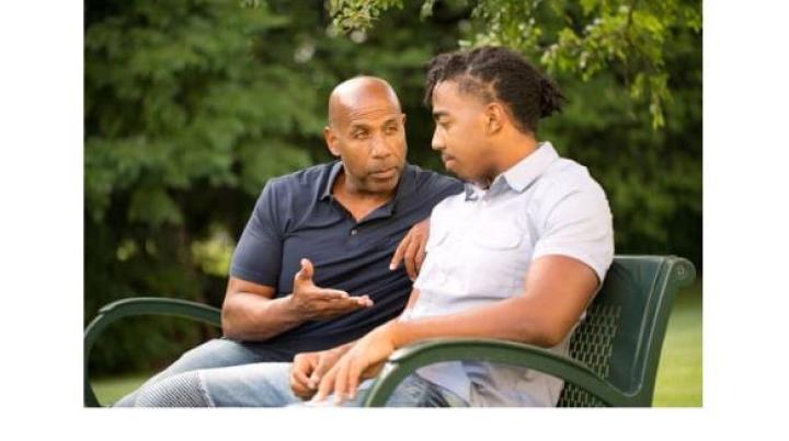 a young man with an intellectual disability is smiling while another young man with red hair holds his shoulders and smiles.