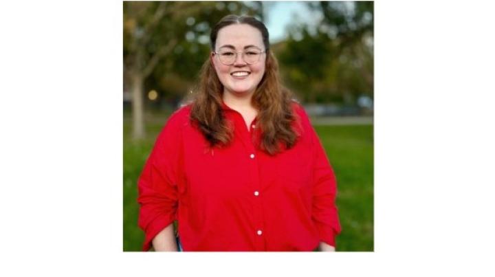 color photo of Hope Sparks, a young white woman with brown shoulder-length hair and glasses wearing a red button down shirt