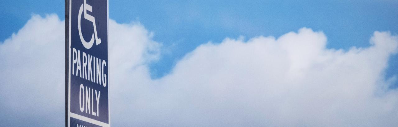 Parking sign against blue sky with clouds