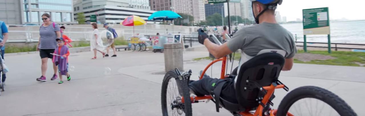 Brad the Bullet Baker riding a hand cycle on a beach in chicago