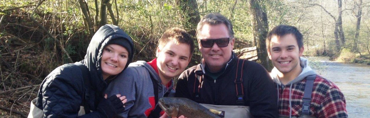 Scott and family in fishing gear holding a fish