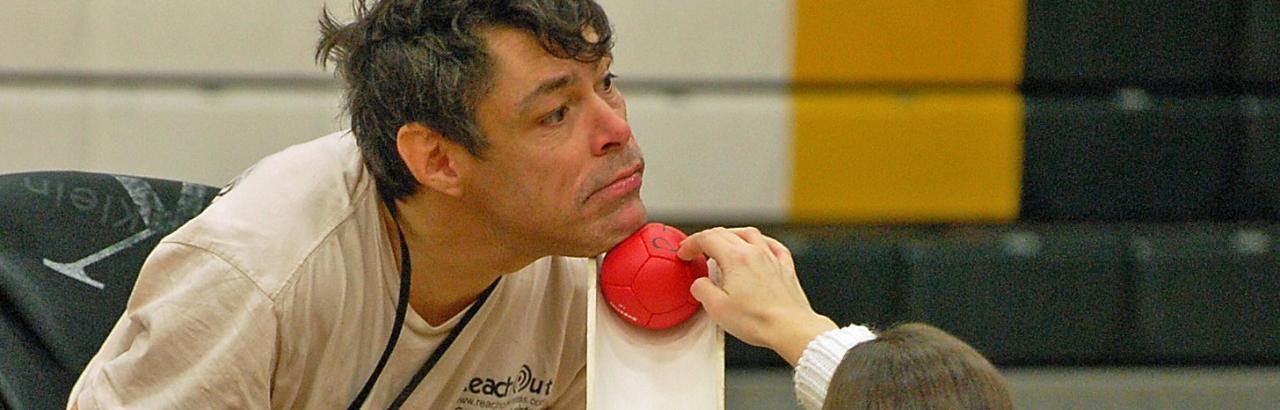 man placing boccia ball onto ramp with his chin 