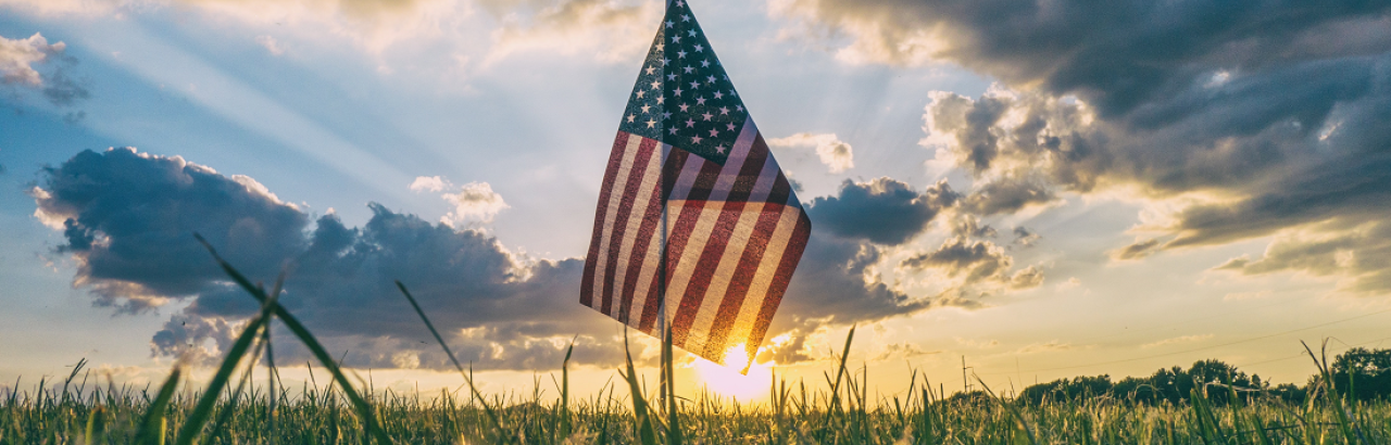 Flag and sunset with clouds and grass