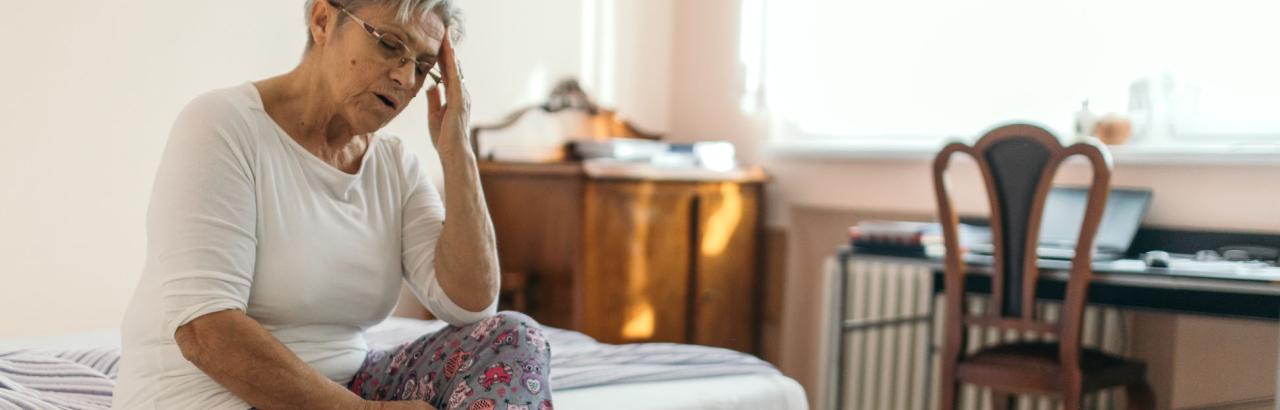 Woman sitting on bed due to vertigo