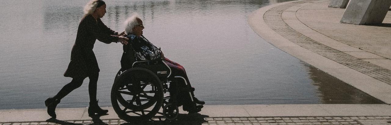 woman pushing man in wheelchair