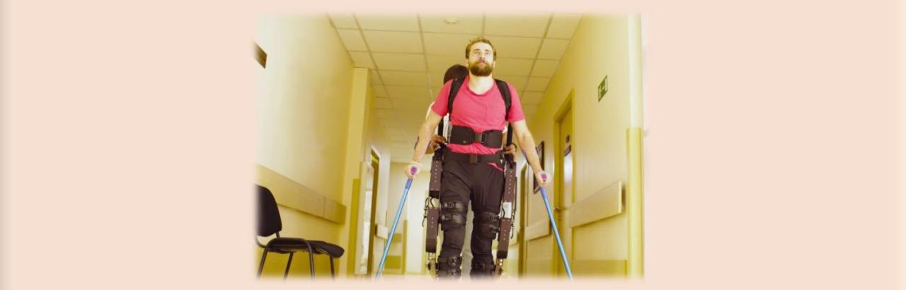 Picture of man walking in an exoskeleton in a hallway.