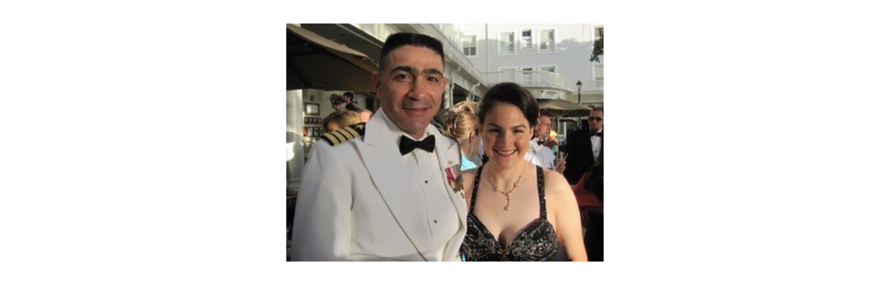 Renee is shown wearing a black dress standing next to a man wearing a white naval suit.