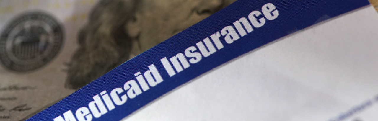 This is an image of a close-up of a Medicaid insurance card over a one hundred dollar bill.