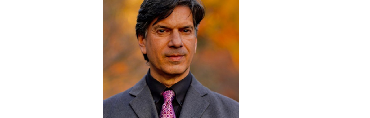 This image shows a headshot of Steven Lutzky in a grey suit with a pink tie and black dress shirt. 