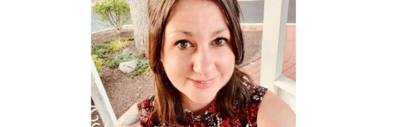 This is a picture of Tonie Sadler. She is wearing a red floral print blouse and taking a selfie.