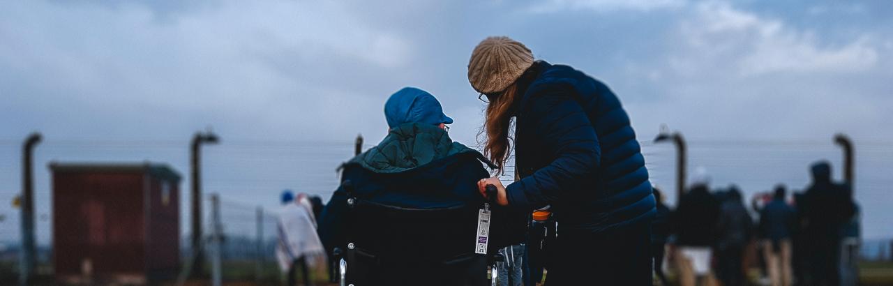 This is a picture of a person in a wheelchair and their family member looking out to a group of people standing in a field.