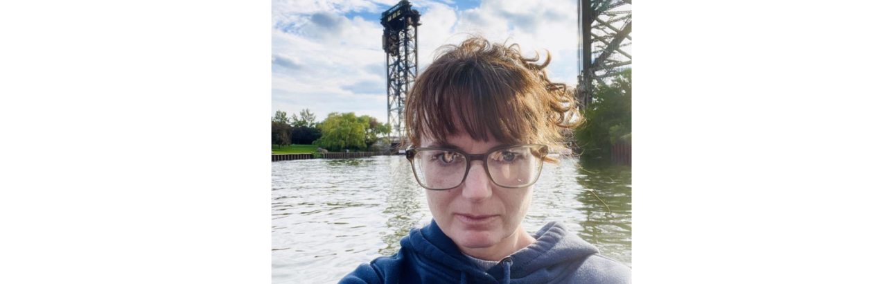 Woman with brown hair and glasses on a boat on a river