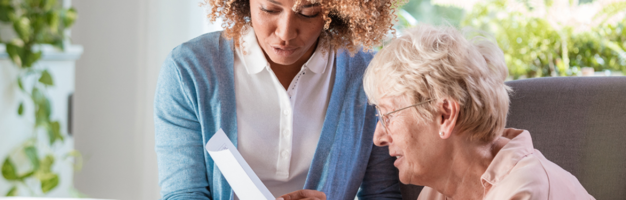 white woman senior with young black woman reading a document together