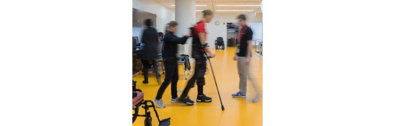 a blurred photo of a person with leg braces practicing walking with clinicans in a hospital setting