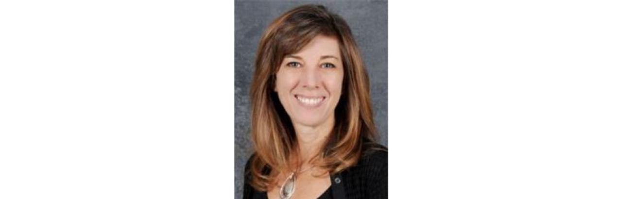 white woman with shoulder length brown hair and a black shirt smiling.