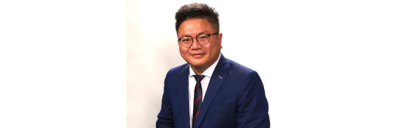 a Chinese man with black hair and glasses wearing a suit is smiling. The picture is black and white