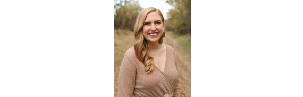 White woman with blonde, shoulder-length hair in a tan sweater outside 