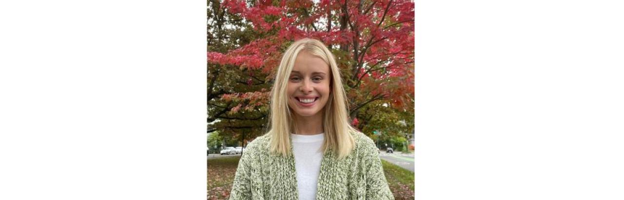 White woman with shoulder length blonde hair wearing a green sweater outside