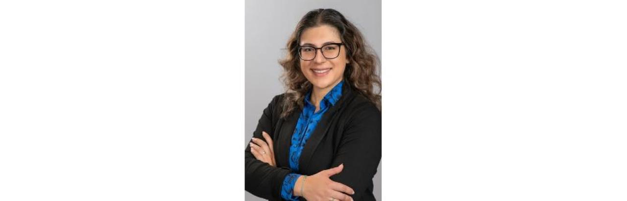 woman in suit with shoulder length brown hair and glasses