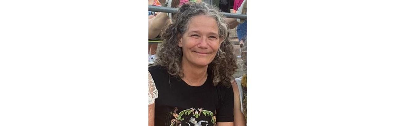 color photo of Mary Curran - woman with curly grey/black hair smiling