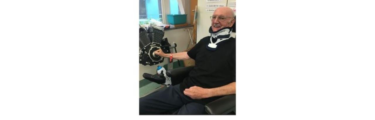 photo of Ian, an older man with glasses in a neck brace at rehabilitation.