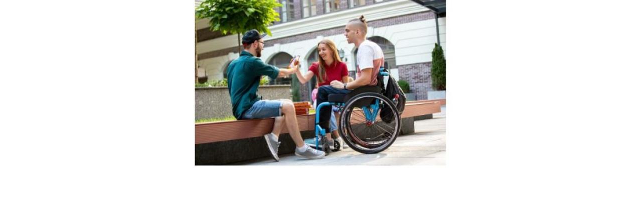 Two young white men and one white woman are sitting outside - one of the men is in a wheelchair.