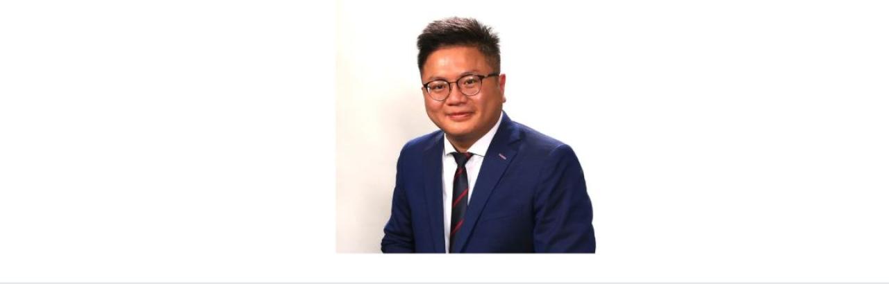 color photo of Alex Wong, a young Chinese man with black hair, glasses wearing a jacket and tie