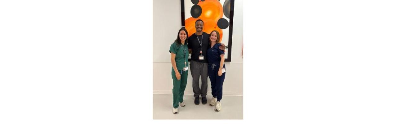 group photo of medical externs - a young white woman in green scrubs with dark hair is on the left, a youhg Black man in gray pants and a black top is in the middle, and a young white woman in navy scrubs with brown hair is on the right.