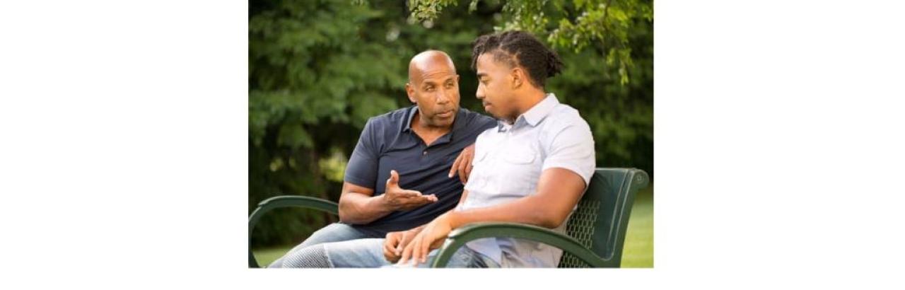 a young man with an intellectual disability is smiling while another young man with red hair holds his shoulders and smiles.