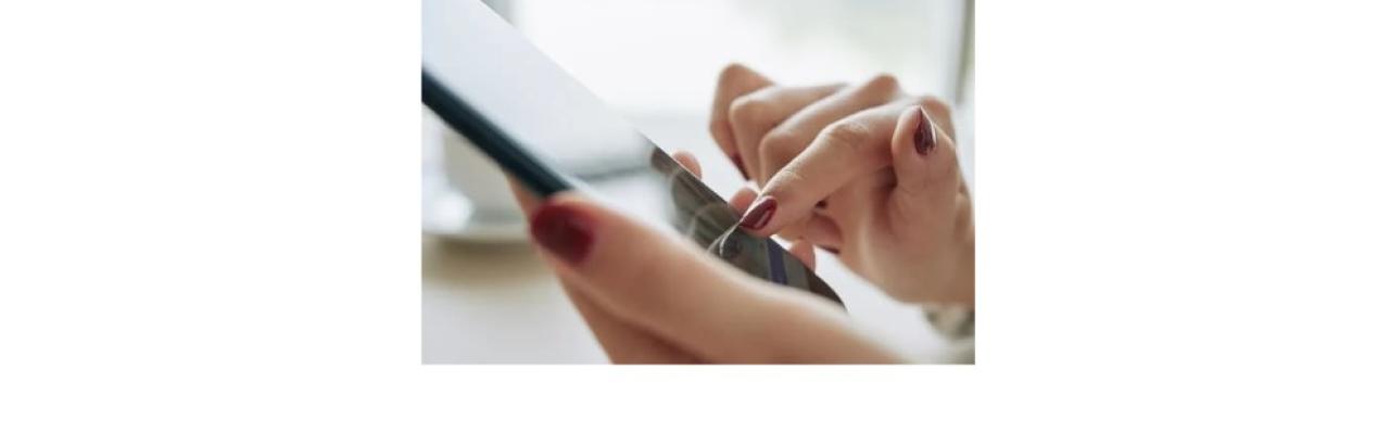 a photo of a pair of white woman's hands with red nail polish holding a cell phone