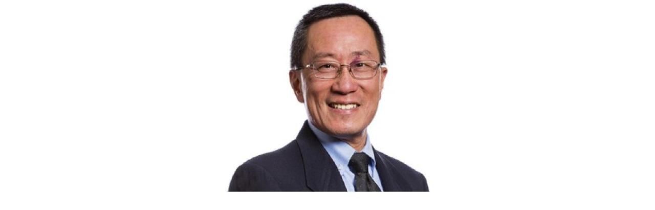 Color photo of Dr. David Chen, a middle aged Asian man wearing glasses and a dark suit with a light blue shirt