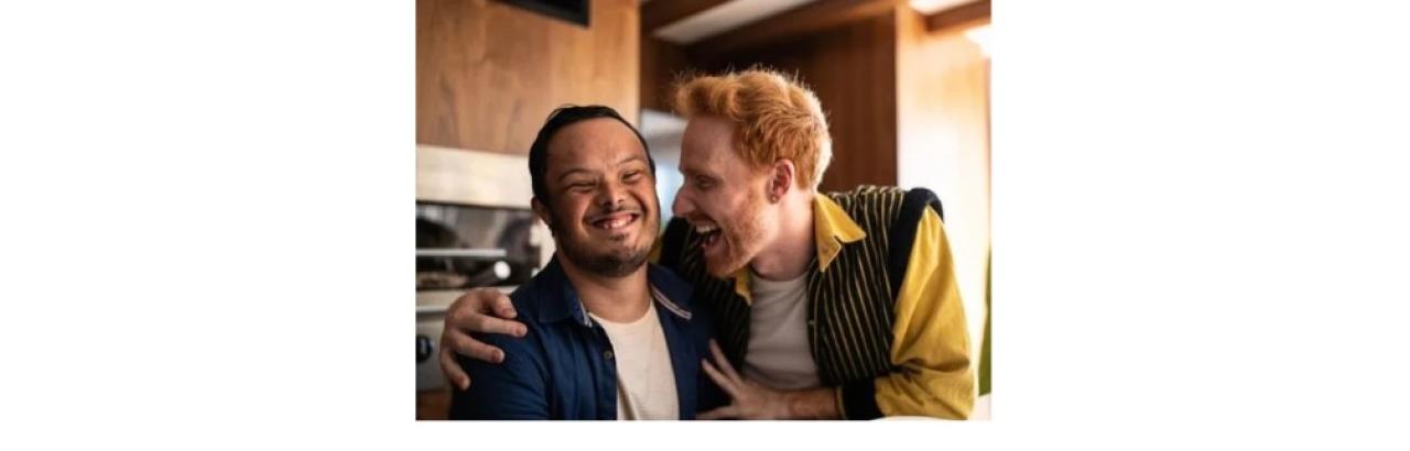 a young adult man with a developmental disabilities and a young white man with red hair giving him a hug. The man with red hair is a DSP