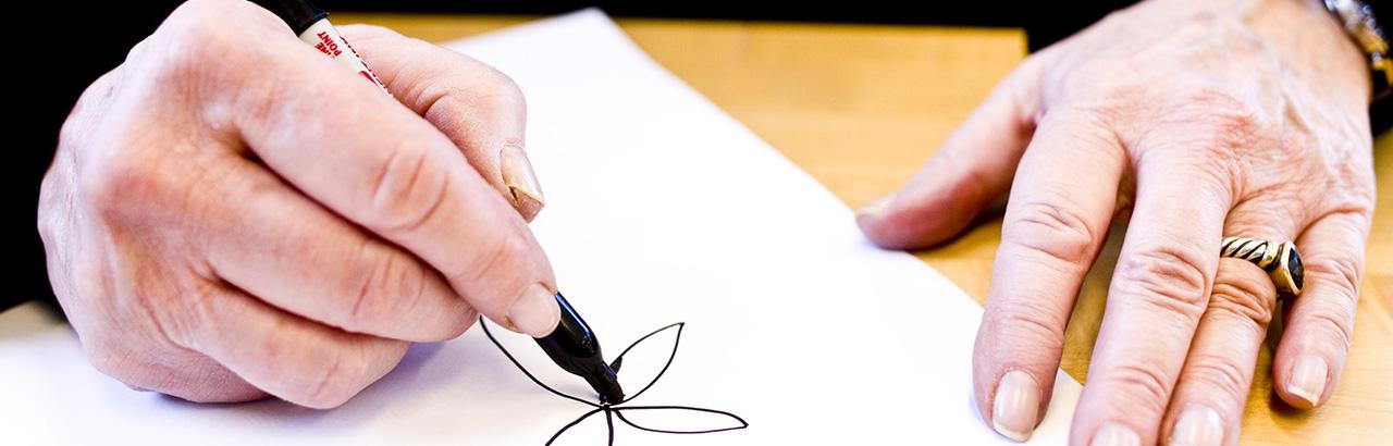 An MS patient works on their fine motor skills by drawing a flower