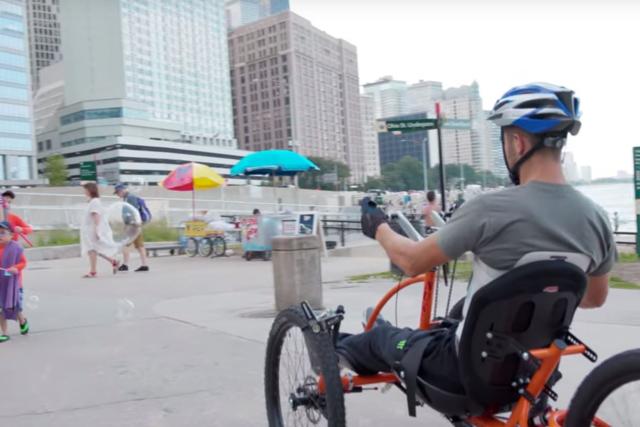 Brad the Bullet Baker riding a hand cycle on a beach in chicago