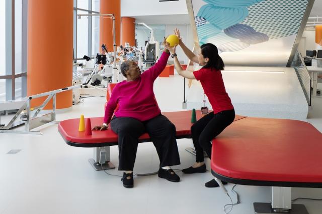 woman physical therapist raising patient arm