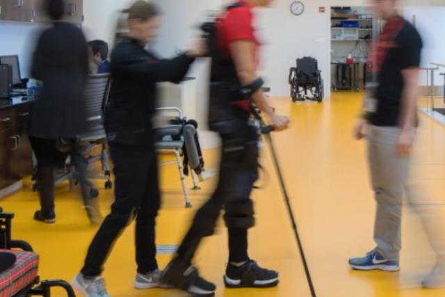 photo of a person walking with a cane being assisted by two therapists