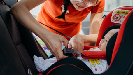 Mom buckling child into car seat