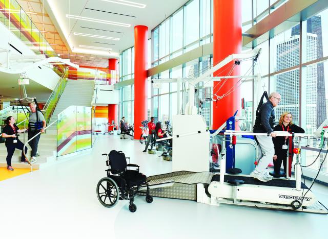 A physical therapist at the Shirley Ryan AbilityLab leads gait training for a patient. The patient’s weight is shared with the lift system, which decreases support as the patient’s ability increases.