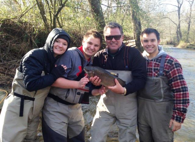 Scott and family in fishing gear holding a fish