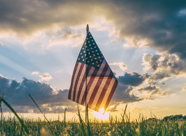Flag and sunset with clouds and grass