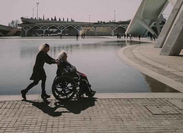 woman pushing man in wheelchair